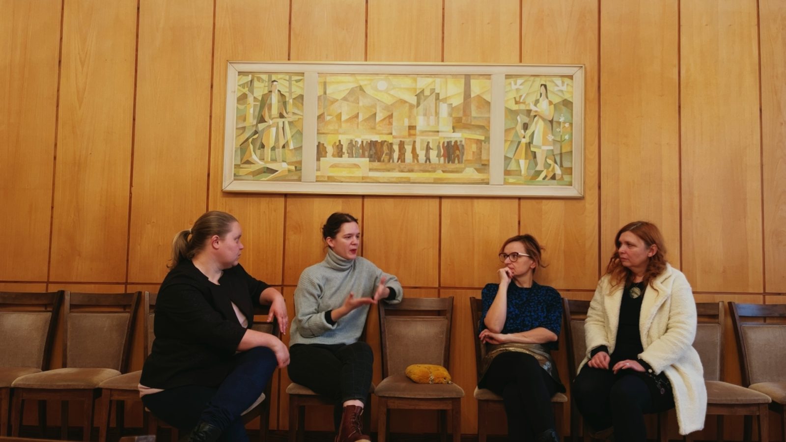 Štyri ženy sedia v miestnosti pod obrazom