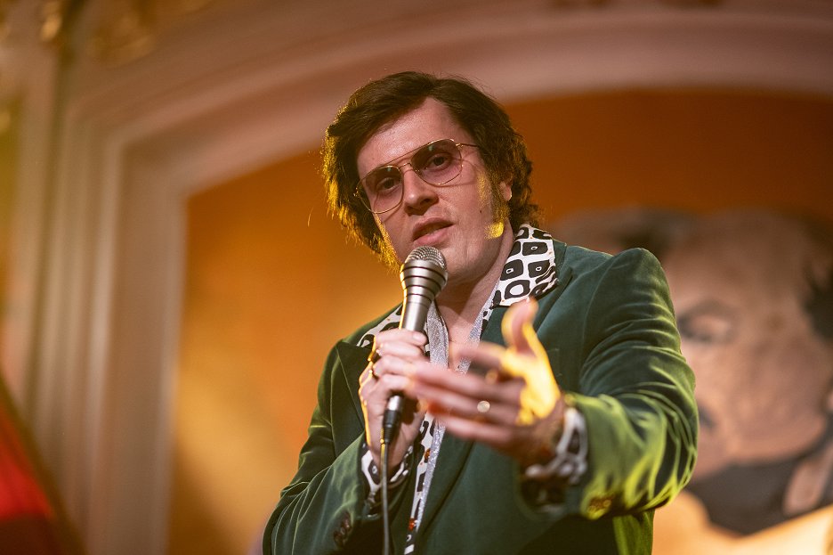 Hlavný hrdina z filmu Duchoň smieva do kamery s mikrofónom v ruke