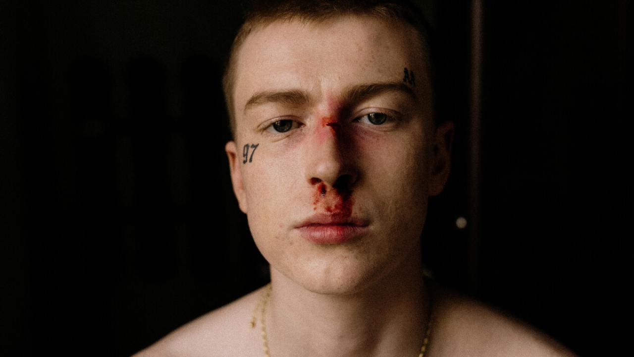 Mladý potetovaný muž odfotený spredu