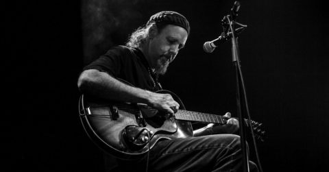 Sir Richard Bishop na pódiu s gitarou a mikrofónom